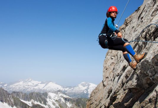 How is Abseiling Insurance different Female abseiling high on a rock