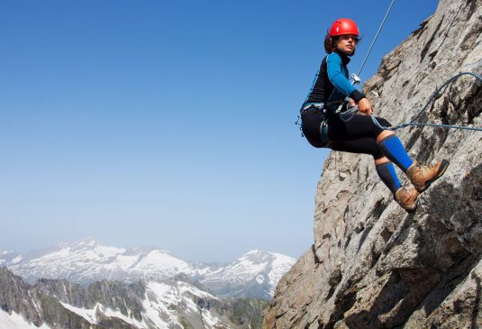 Female abseiling high on a rock